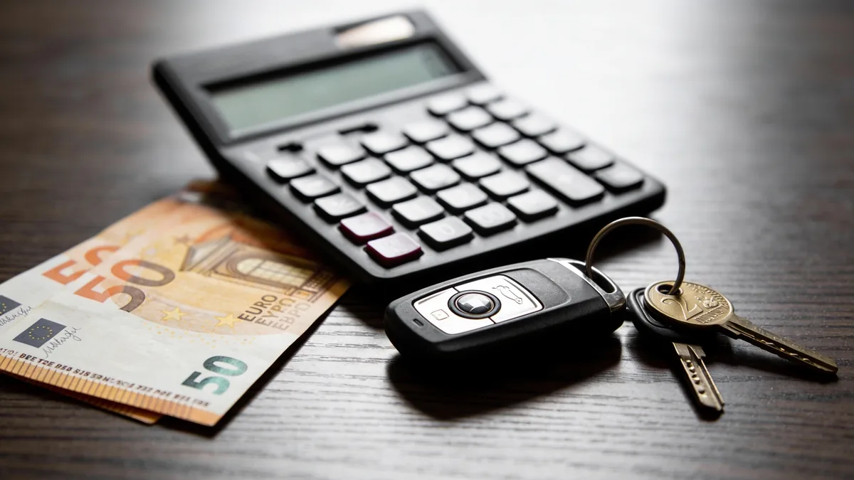 Calculadora, llaves de coche y billetes de euro representando el cálculo de la cuota de financiación de un coche chino